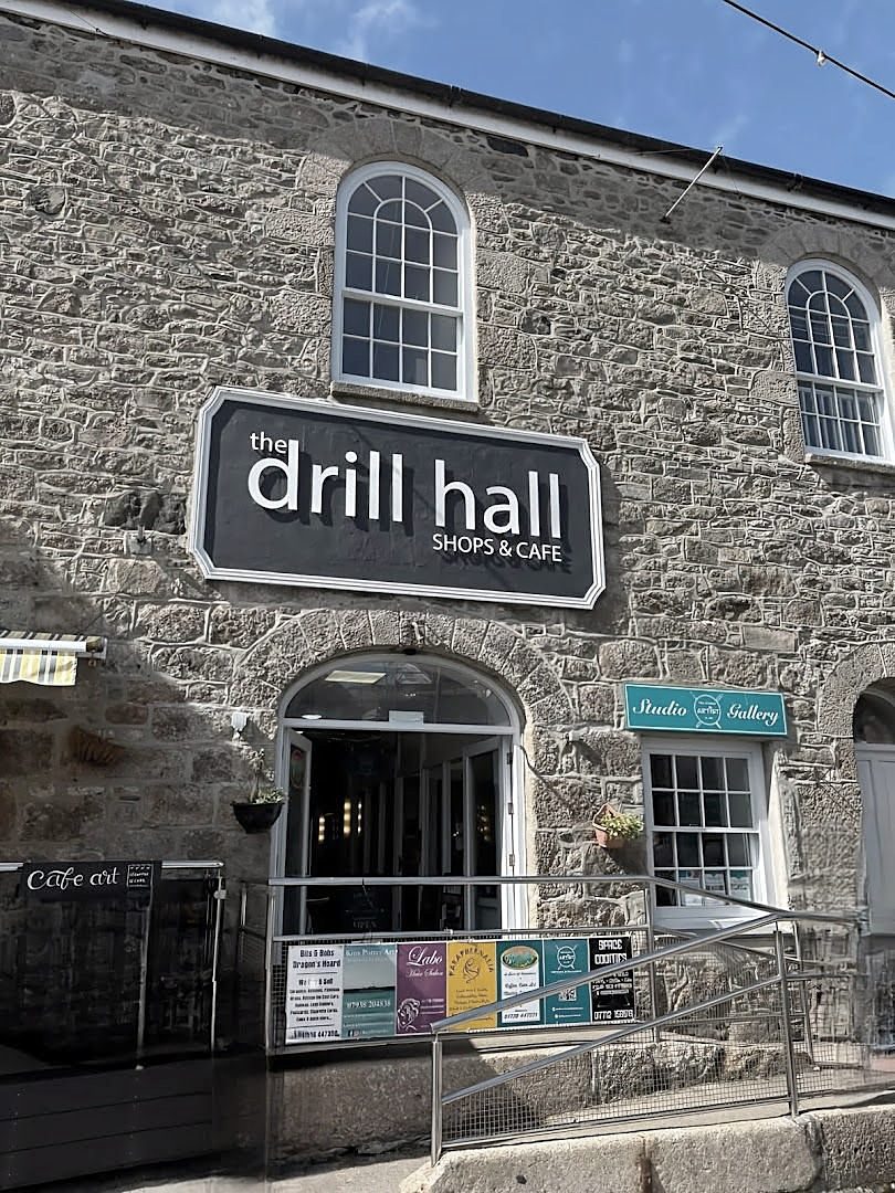 The Drill Hall on Chapel Street: a granite front with arched windows, an arched doorway and a black sign reading 'the drill hall, shops & cafe'